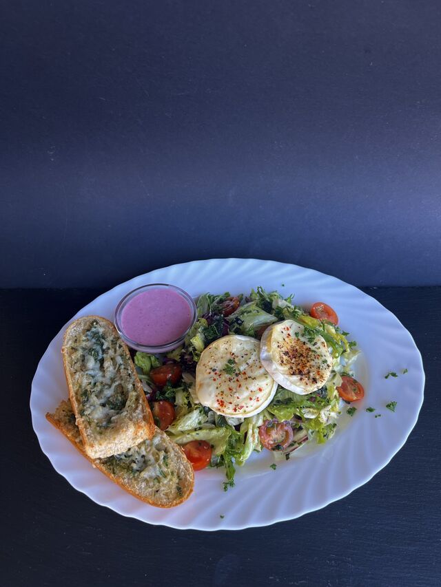 Míchaný listový salát s grilovaným hermelínem a brusinkami, rozpečená bageta s bylinkovým máslem