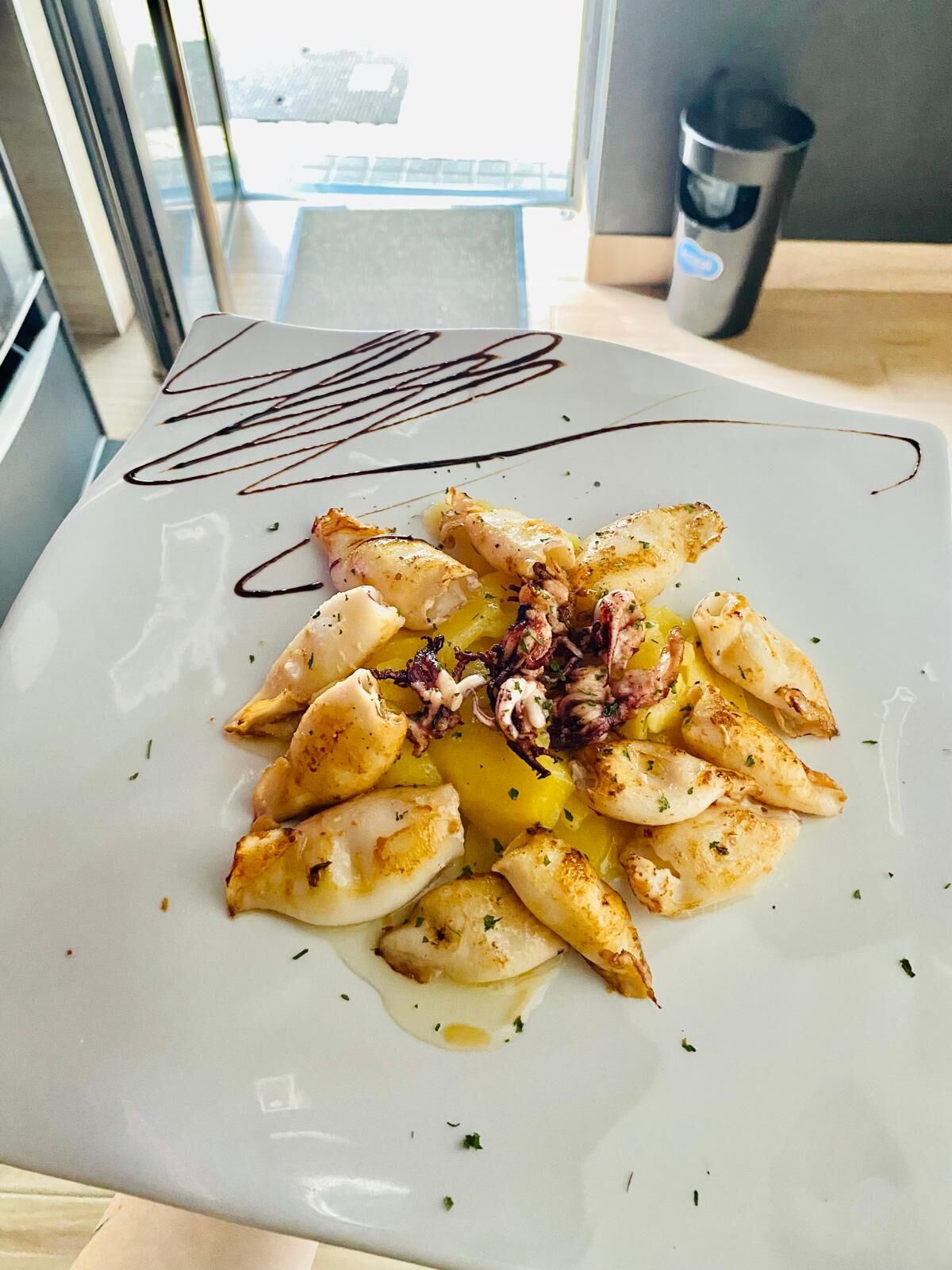 Chipirones a la plancha sobre cama de patatas panaderas 