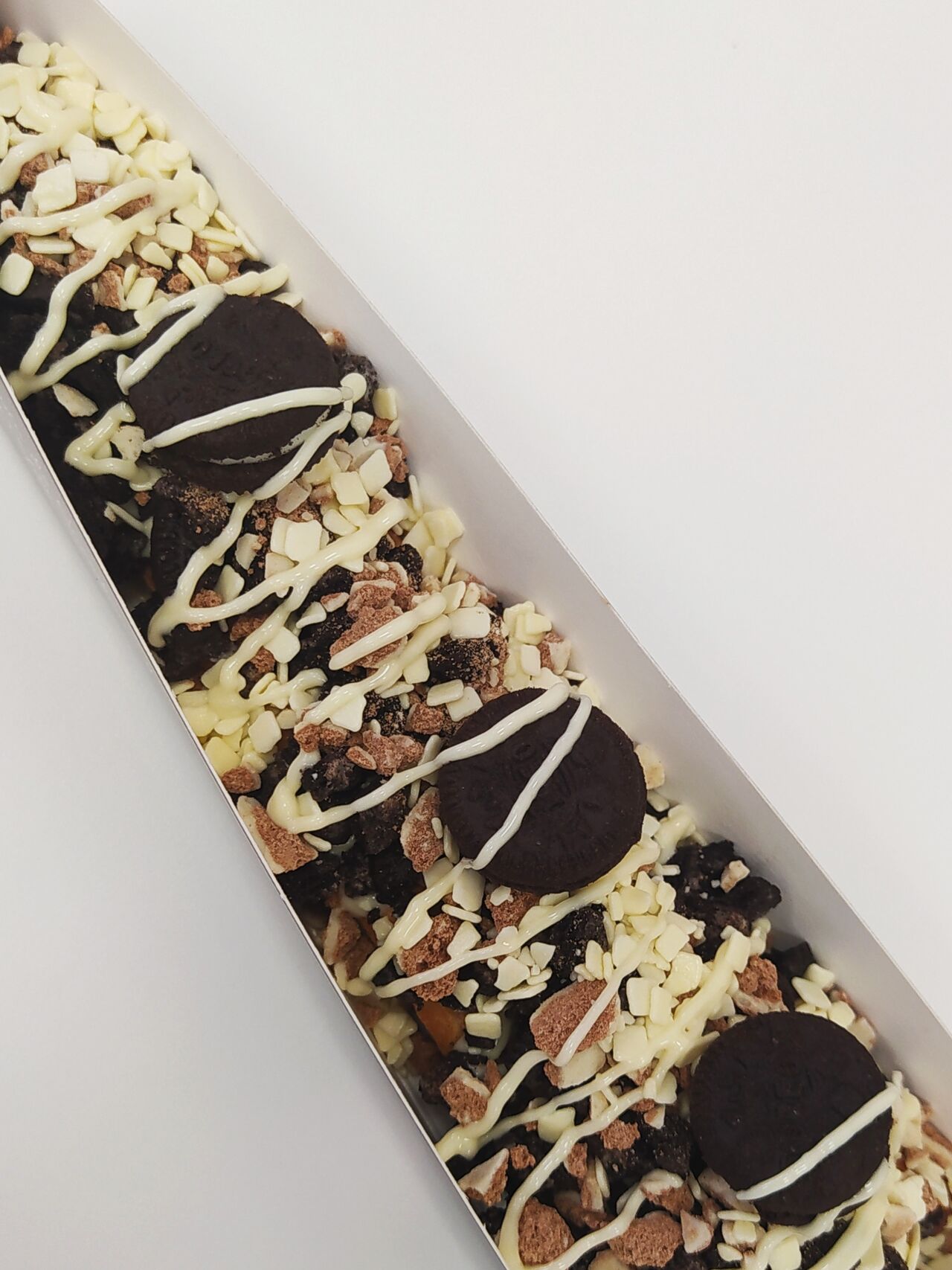 Gofre piruleta con salsa ferrero rocher, salsa de chocolate blanco, Oreo, filipinos, y virutas de chocolate blanco
