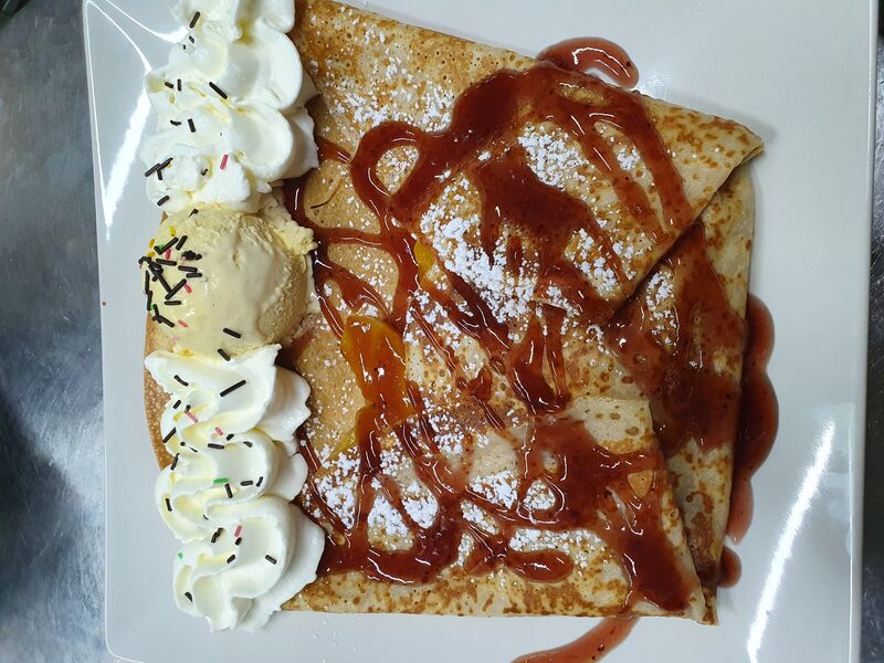 Crêpe Melba, crêpe dulce con melocotón en almíbar, sirope de fresa, helado de vainilla y nata montada.