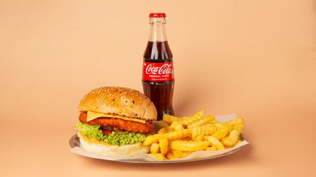 Crispy-Chicken-Burger mit Cheddarkäse, Tomaten, Salat, saure Gurke und roten Zwiebeln