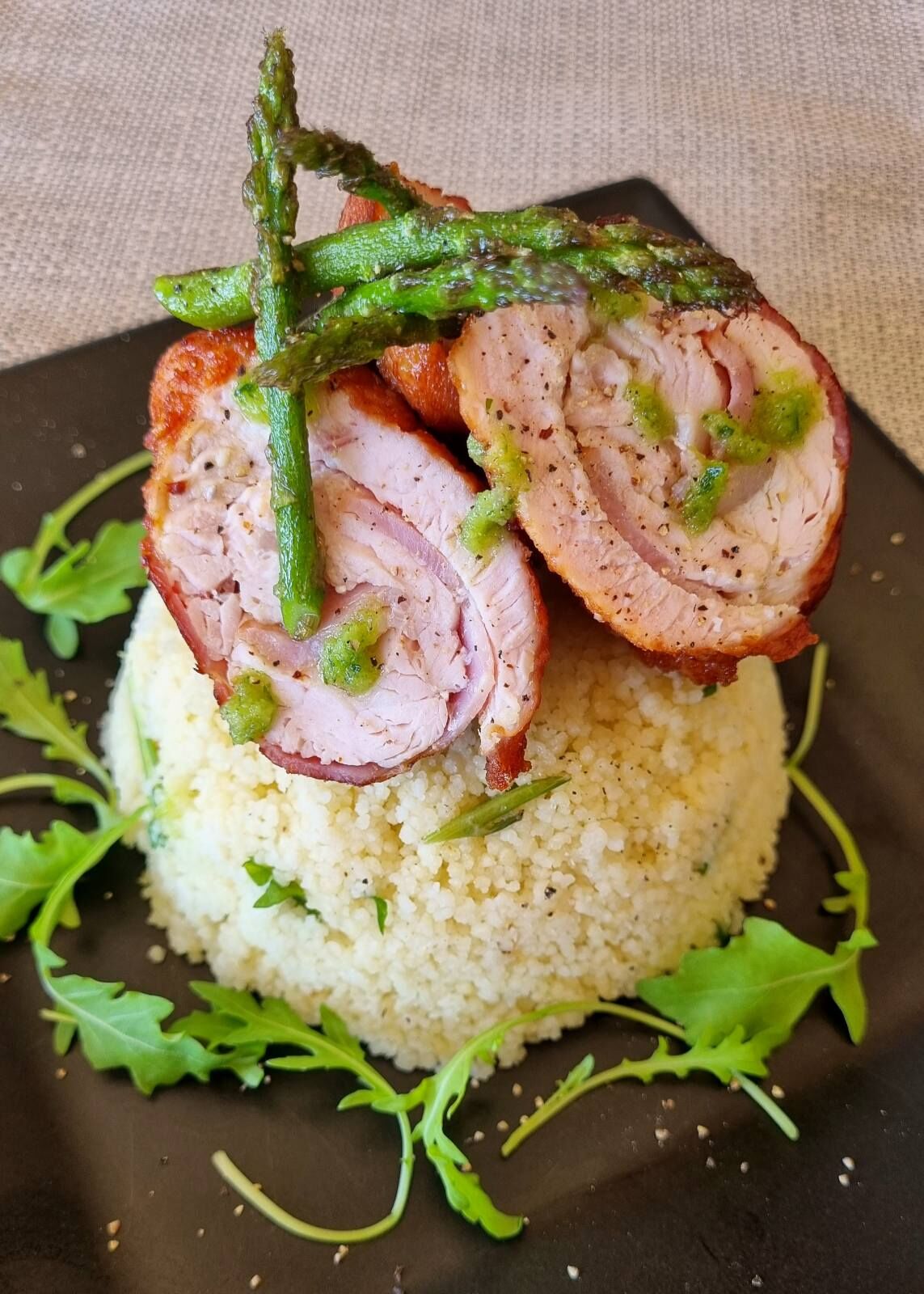 Pechuga de pavo asada enrollada en tocino con couscous y esparragos asado, salsa de ayo y perejil