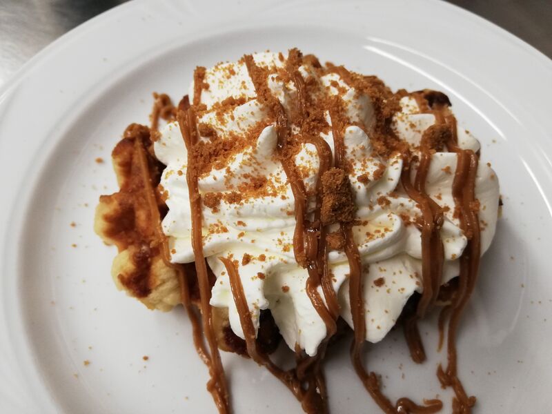 Gepimpte, verse suikerwafel met slagroom en speculaascrunch en speculaastopping.