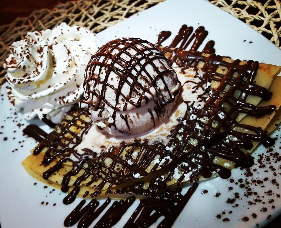 Crepes con chocolate negro y una deliciosa bola de helado de fresa acompañado de nata, una combinación para los atrevidos