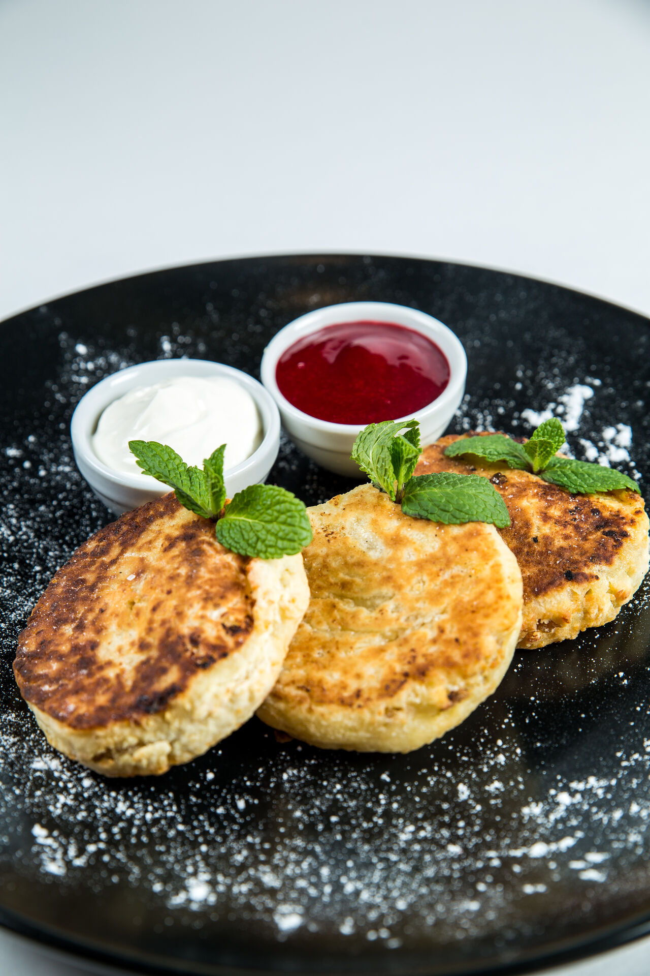 Сирники по-домашньому зі сметаною та джемом.