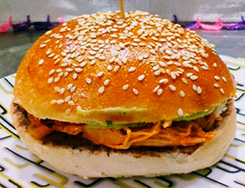 Cemitas de pollo tinga: Pain burger, purée de haricot noir, farce à la tinga de pollo et guacamole