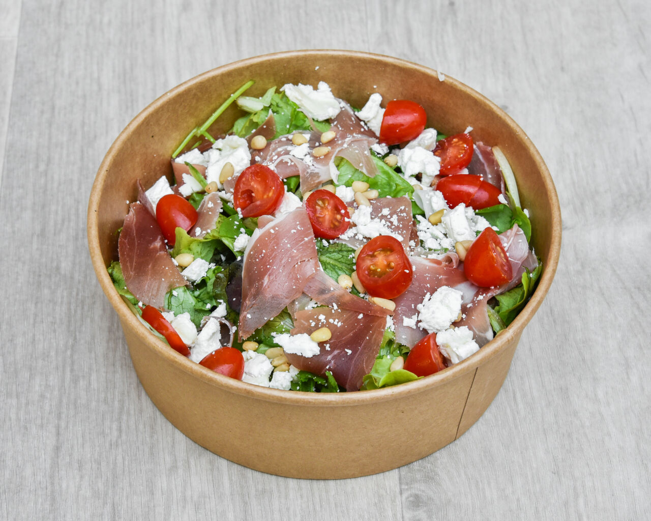 Salade, jambon de Parme, tomates cerises, chèvre et pignons. Base et sauce au choix.