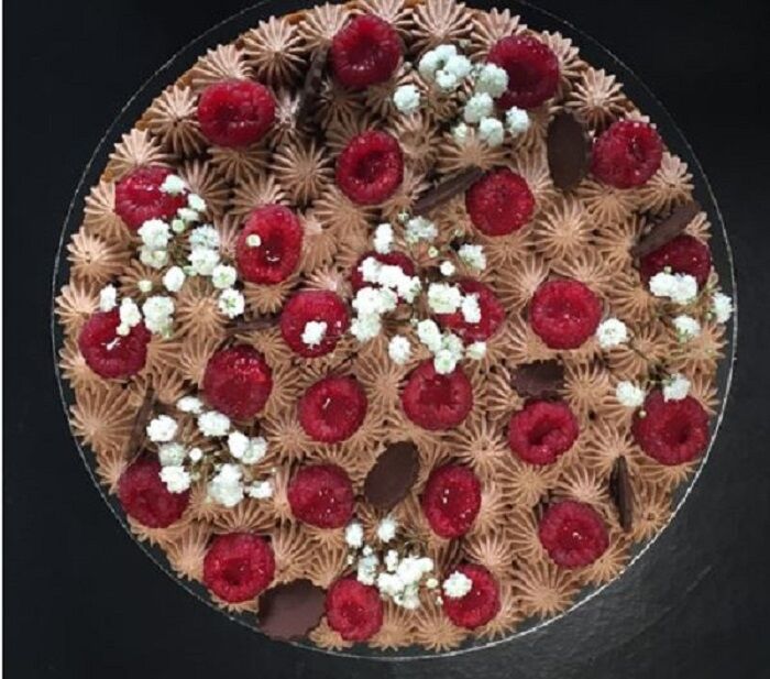 La Surprenante : Croustillant aux noisettes, Crémeux chocolat lait et framboises, Fleurs chocolat noir, Framboises avec coulis