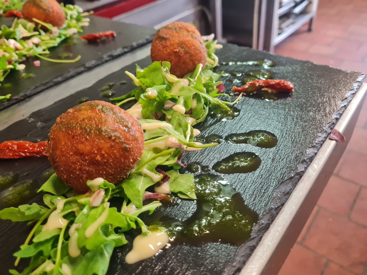  Ardoise d'Arancini ,sur un lit de roquette ,arancini farcie a la mozzarella et huile de basilique. pesto maison