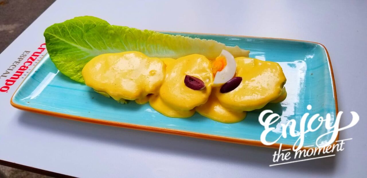 Papa a la Huancaína:
Salsa de Queso y Ají Amarillo sobre crujientes papas doradas, servido con Lechuga, Huevo duro y Aceituna.
