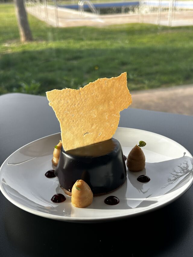 Mousse de Chocolate con glaseado espejo, gancho de caramelo, coulis de frutos rojos y pasta cigarrillo 