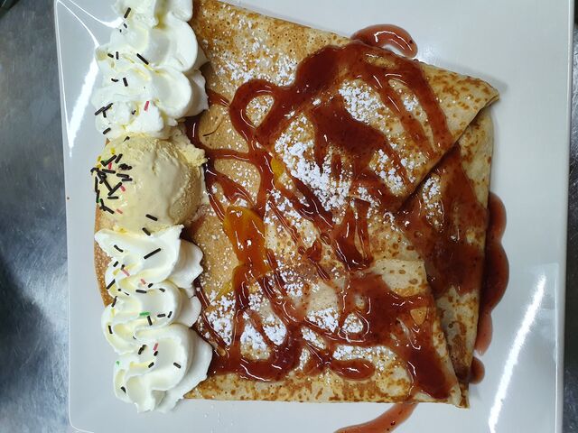 Crêpe Melba, crêpe dulce con melocotón en almíbar, sirope de fresa, helado de vainilla y nata montada.