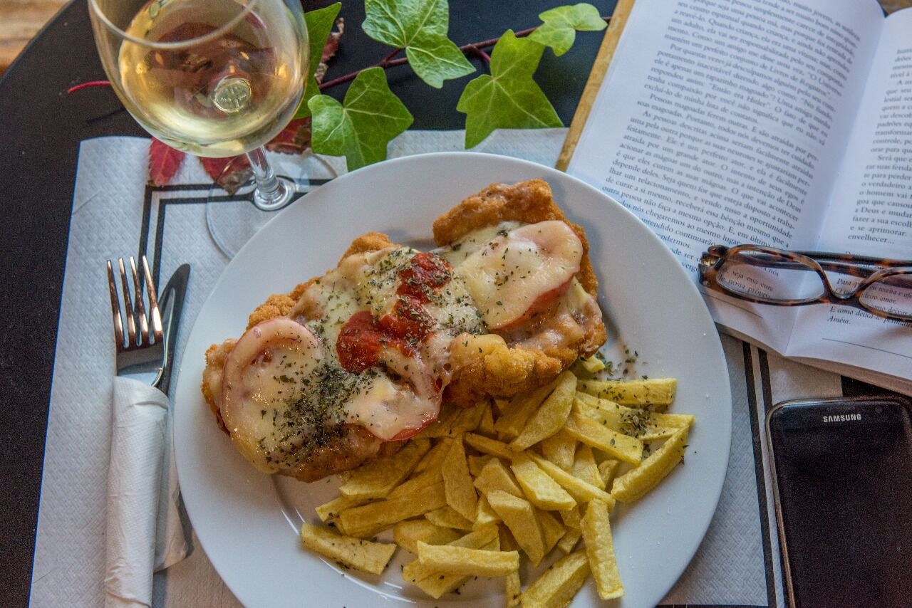 Filete de pechuga de pollo empanado con salsa de tomate fresca, queso mozzarella fundido y orégano acompañada de patatas fritas
