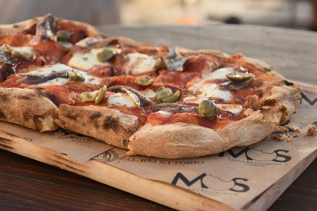 Pinsa romana, pomodoro, fior di latte, alici del Cantabrico, capperi e origano