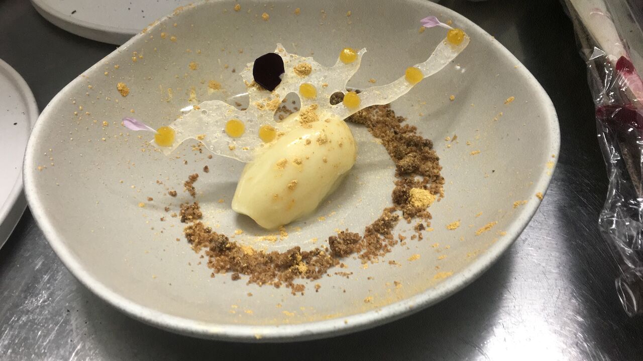 Cremoso de chocolate blanco con cristales de menta acompañado de unos puntos de gel de mango (nuestros menús semanales varían)