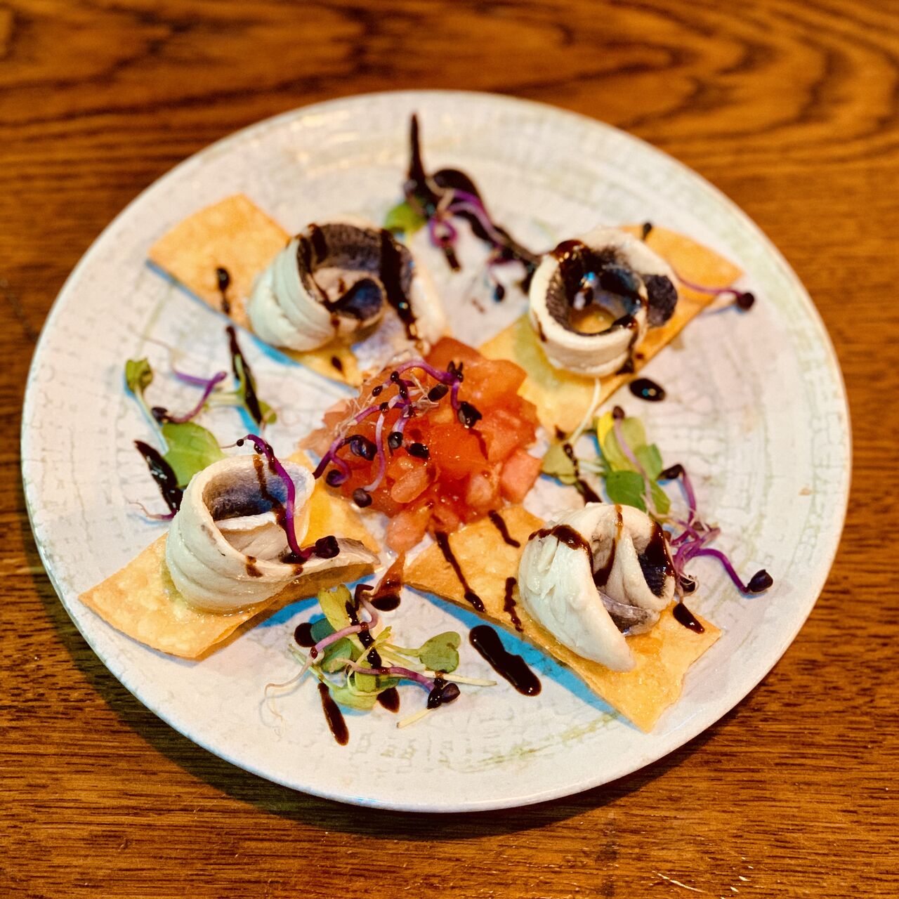 Boquerones en vinagre sobre tiras crujientes de maíz, tartar de tomate y sus germinados