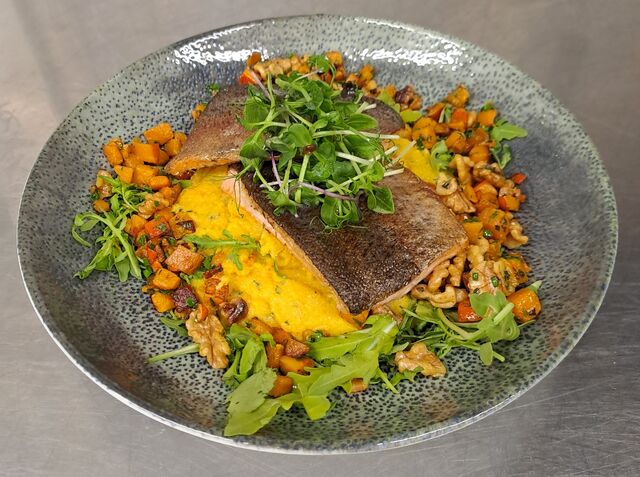Lachsforellenfilet mit Kürbis-Rahmpolenta, Rucola und Nüssen