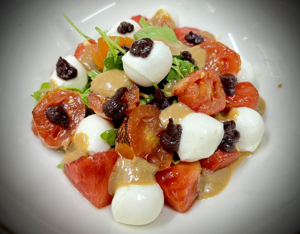 Ensalada de sandía marinada con mozarella, tomates confitados, olivada y salsa de sésamo 