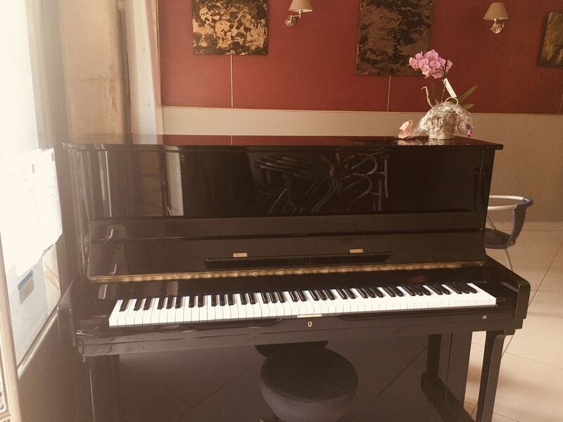 Notre Piano qui est à Votre Disposition, ainsi que l’Exposition de Peinture en arrière plan