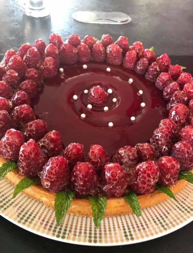 Tarte aux fruits rouges avec un sablé , une crème d'amandes une gelée de framboises et framboises , quelques feuilles de menthe.