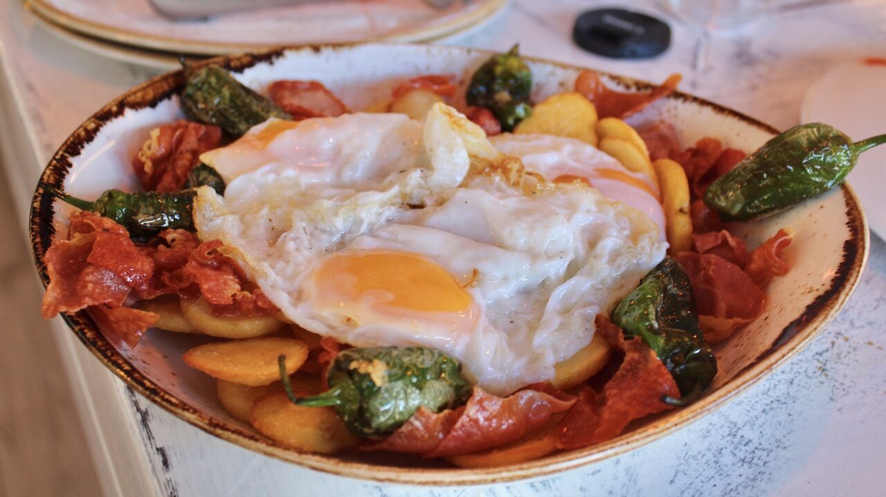 Huevos rotos con jamón y pimientos de padrón 