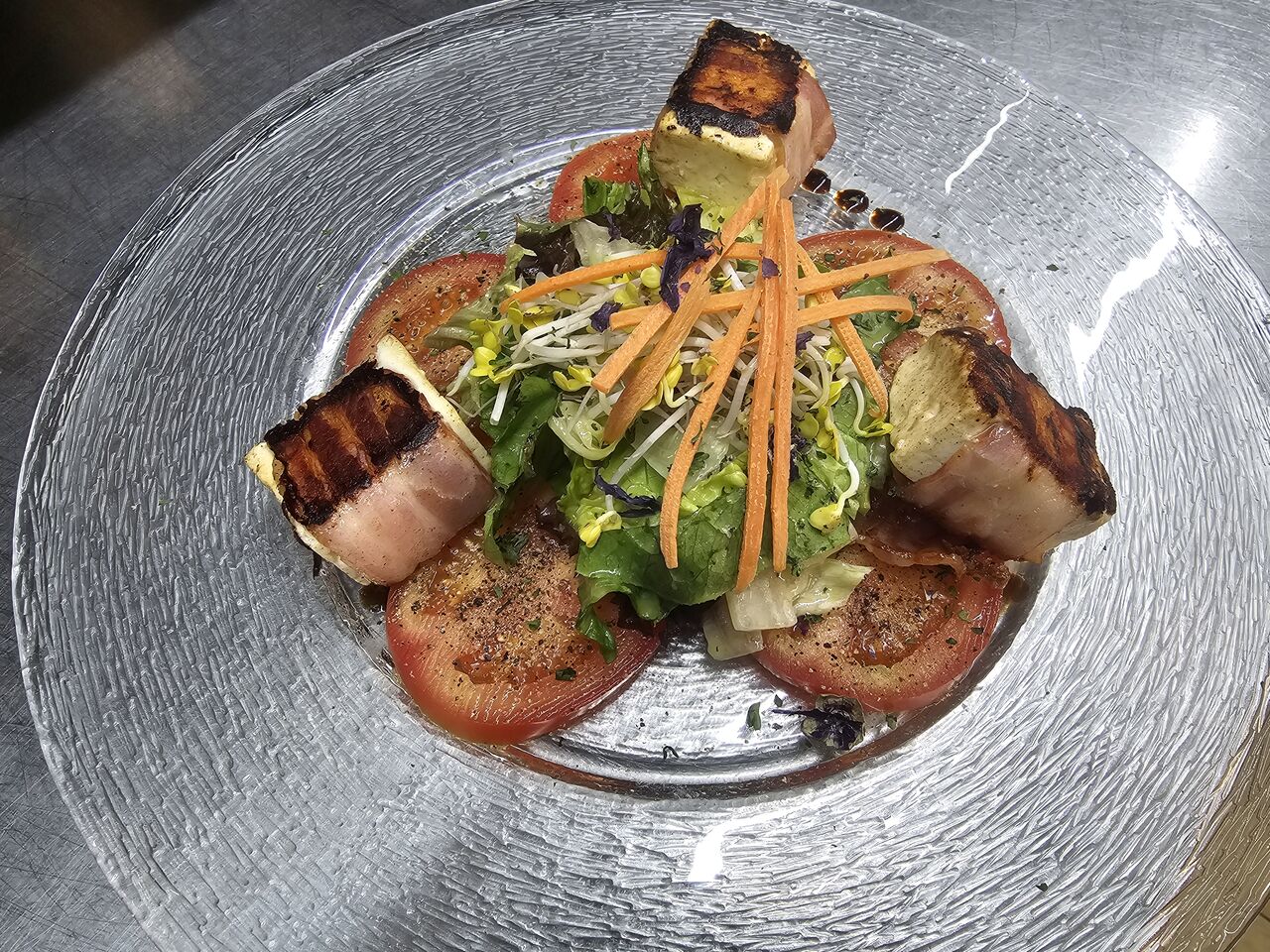 Vorspeise: gegrillter Schafskäse im Speckmantel auf Tomaten Carpaccio und Salat Bukett