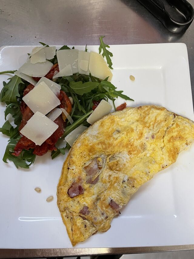 Omelet met spek en Italiaanse slaatje op een bordje 