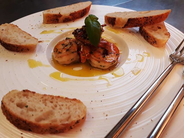 eine Vorspeise - gebratene White Tiger Garnelen mit Chili und Knoblauch, serviert mit Brot und Oliven