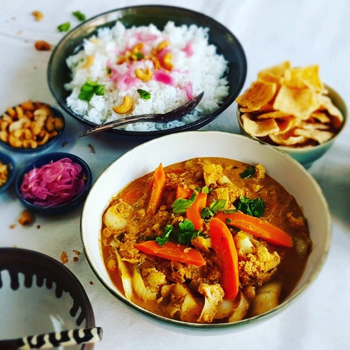 Indiase groentencurry met ingelegde rode ui, cassavechips, witte rijst en geroosterde cashewnoten