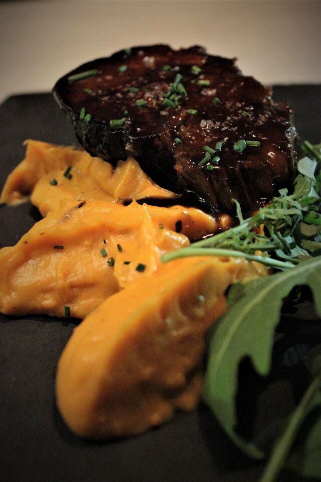 BONDIOLA Aguja de cerdo horneada a baja temperatura con salsa de cerveza Guinness y emulsión de batata, puerro y naranja asada