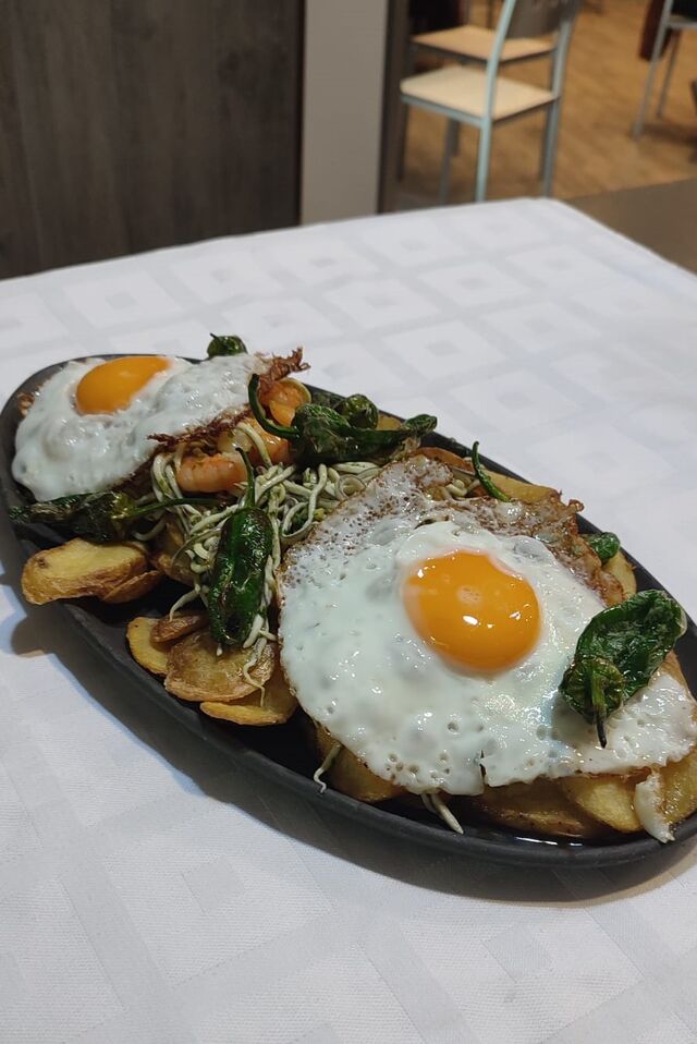 Huevos rotos con gulas y gambas