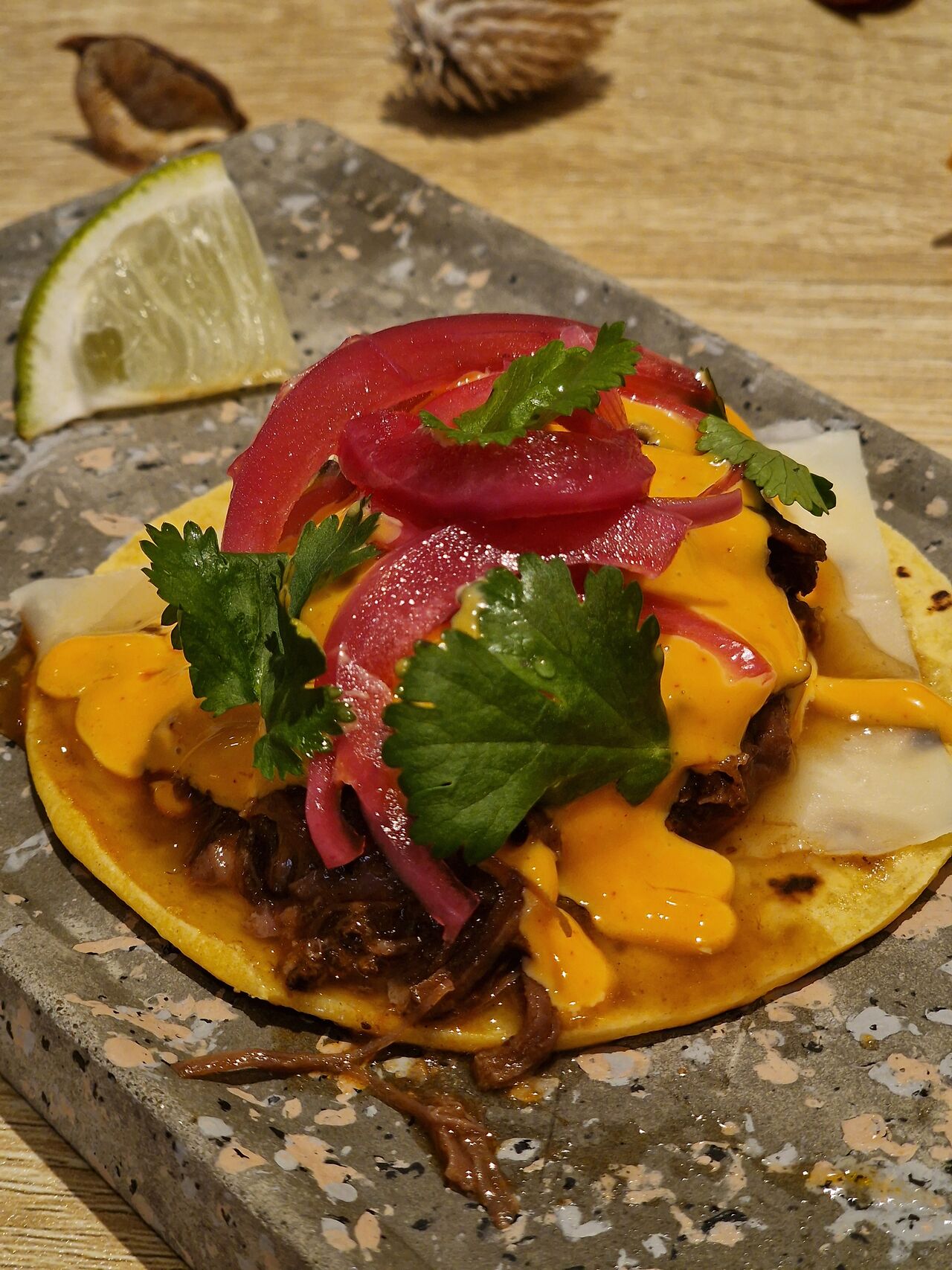Taco de carrilleras, con provolone, cebolla encurtida y salsa Emmy