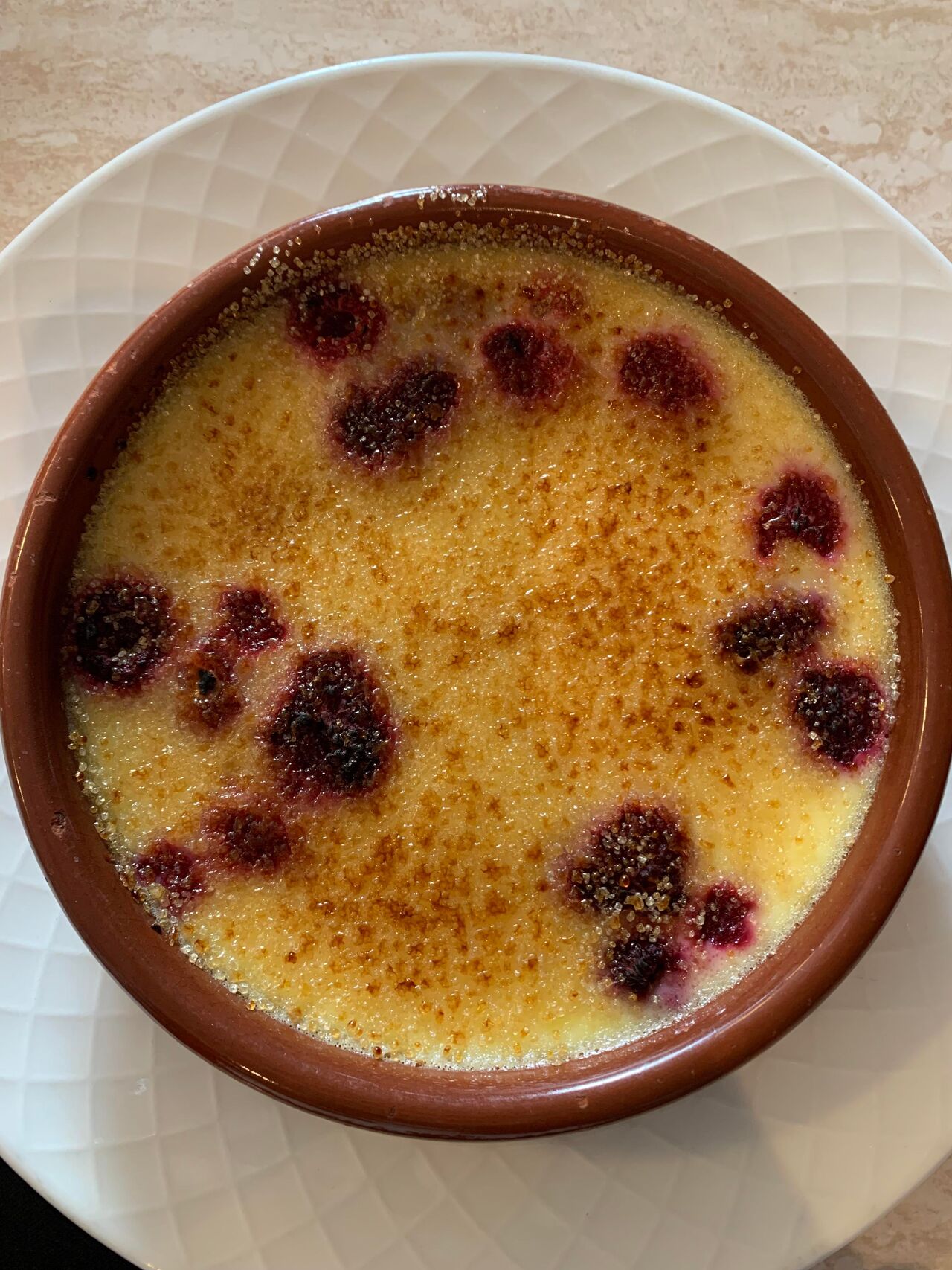 Crème brulée accompagnée de ses framboises