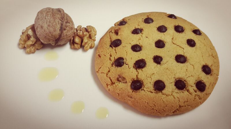 Uma deliciosa cookie com azeite, pedaços de noz no interior, pepitas de chocolate no topo. Quantidades mínimas: caixa de 6