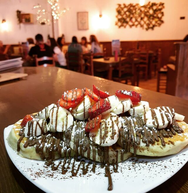 Deliciosas tortitas americanas con chocolate con leche, plátano y fresas.