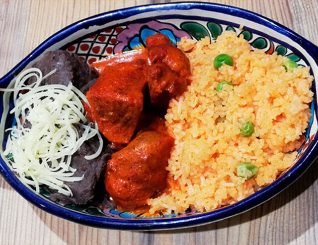 Cochinita Pibil: Ragoût de porc mariné dans l'Achiote légèrement pimenté. Accompagné de riz et d'une purée de haricots noirs