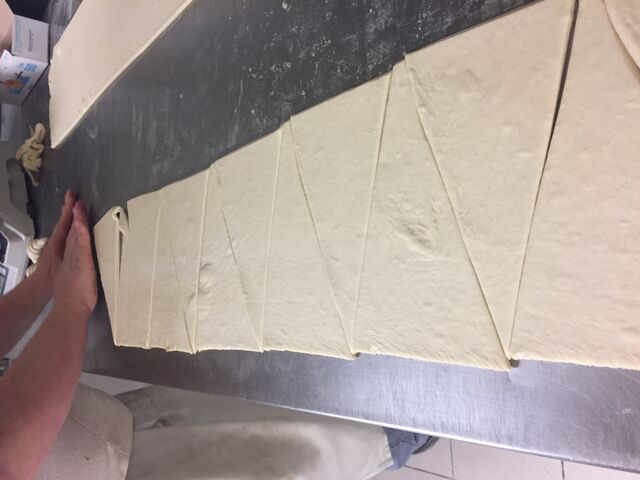 Le pâtissier en pleine préparation pour réaliser des croissants au beurre 