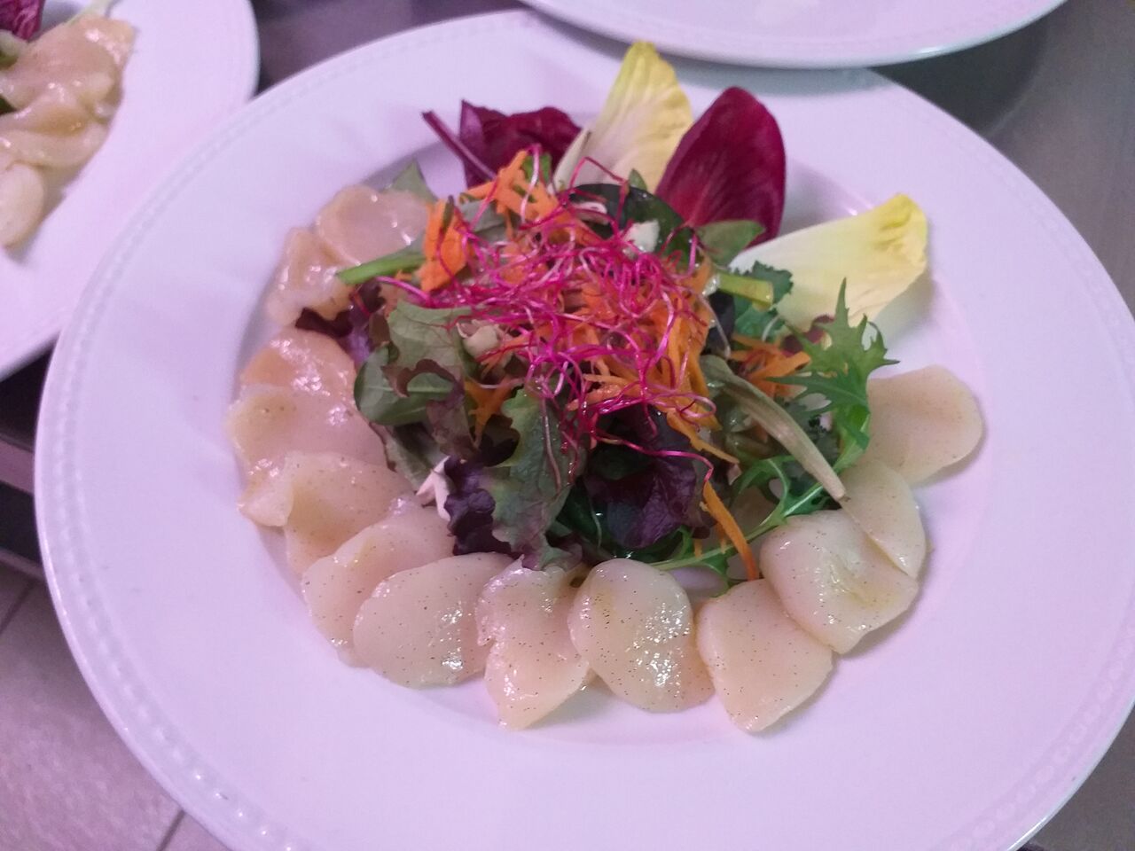 Salade de jeunes pousses et carpaccio de noix de saint Jacques blanches à la vanille.