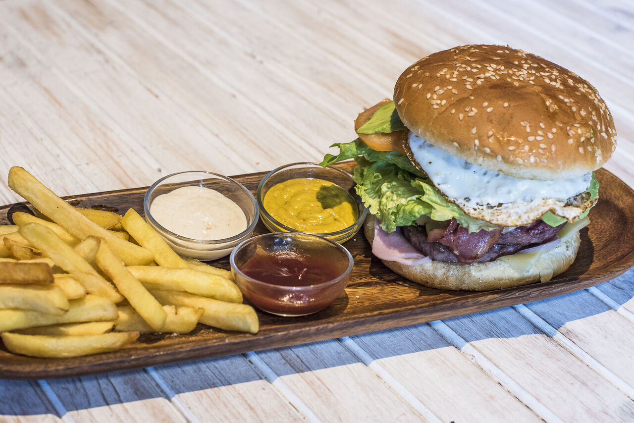 Hamburguesa XL de carne de ternera con huevo, bacón, aguacate, jamón, queso, lechuga, tomate, cebolla, salsas y patatas fritas