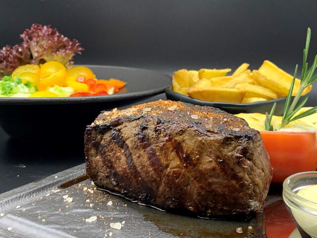 300g argentinisches Black Angus Striploin (Rumpsteak) mit hausgemachter Kräuterbutter, Steakhouse Fries und einem Salatteller