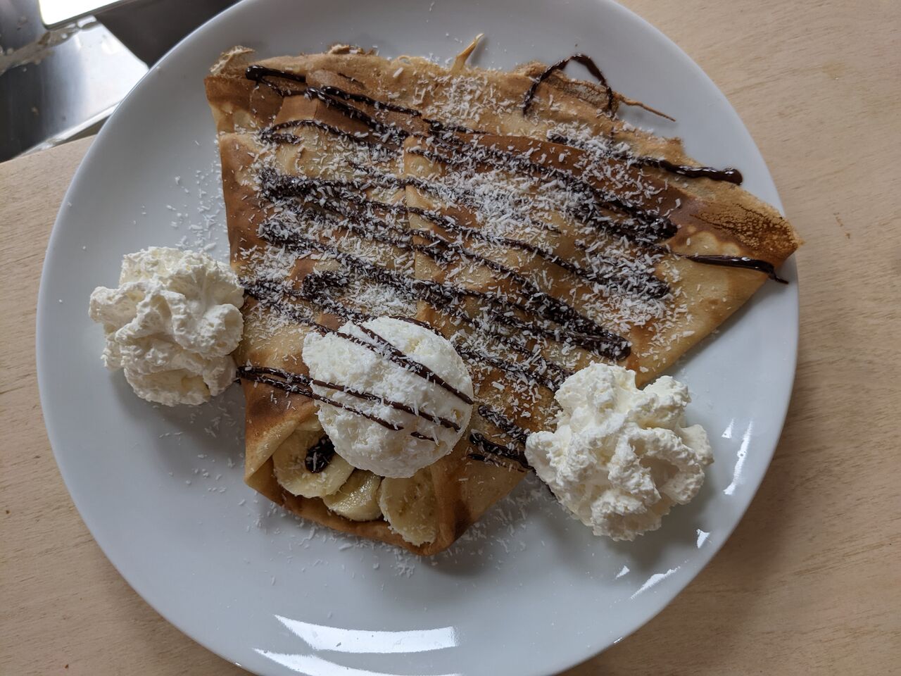 La BIG, crêpe de froment avec banane, chocolat noir maison, boule de glace coco, coco râpé et chantilly maison