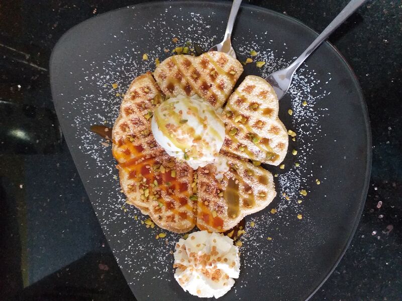 Heiße Waffel mit Siciliano Eis, Pistaziensoße, gehackten Pistazien und Sahne
