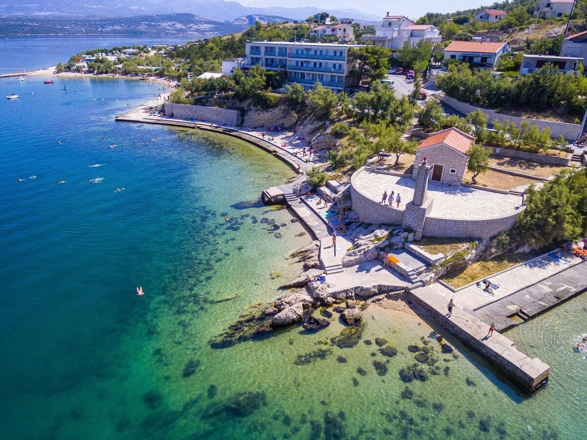 There is small lighthouse in front of church Saint Nicholas and hotel is in the back of the photo