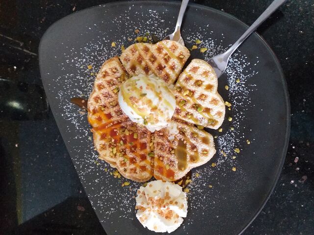 Heiße Waffel mit Siciliano Eis, Pistaziensoße, gehackten Pistazien und Sahne 