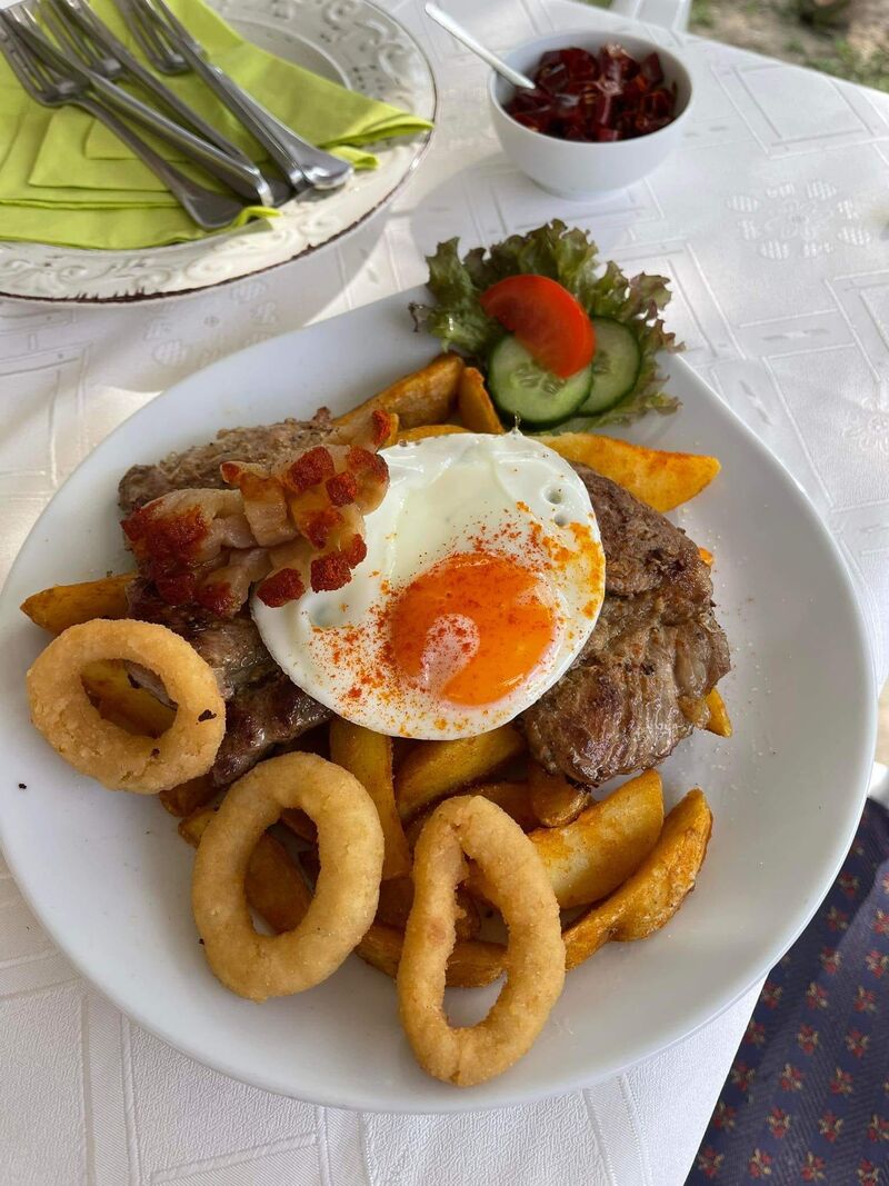 Fokhagymás óriás sült tarja ropogós hagymakarikával tükörtojással, szalonnával, héjában főtt, sült burgonyával 