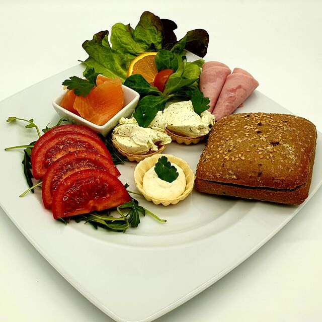 Feinschmecker Frühstück - warmes Mehrkornbrötchen, Frischkäse, Kochschinken, Räucherlachs, Meerrettich, Rucola, Tomaten