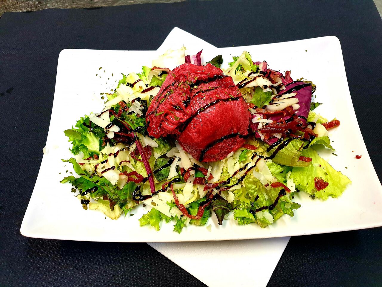 Ensalada con helado de frutos del bosque, queso manchego y lascas de jamón ibérico.