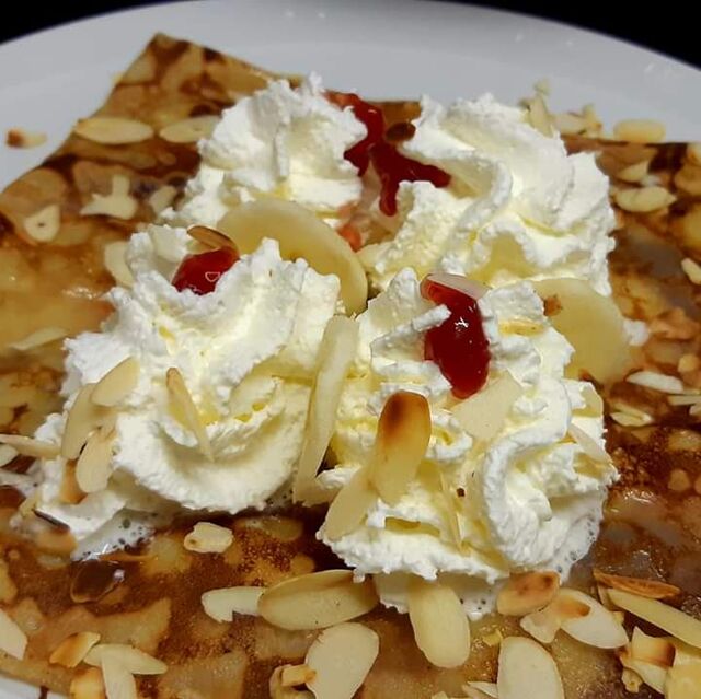 Crêpe dessert banane, gelée de groseille, crème fouettée et amandes effilées grillées.