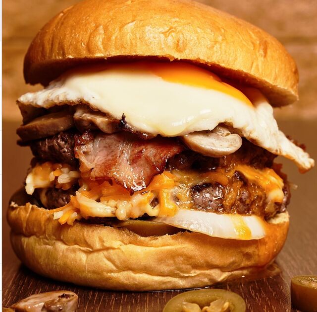 HAMBURGUESA DE LA CASA DOBLE CARNE DE RES RELLENAS QUESO Y BEICON, HUEVO ENSALADA LAMINA DE BEICON QUESO Y SALSAS 