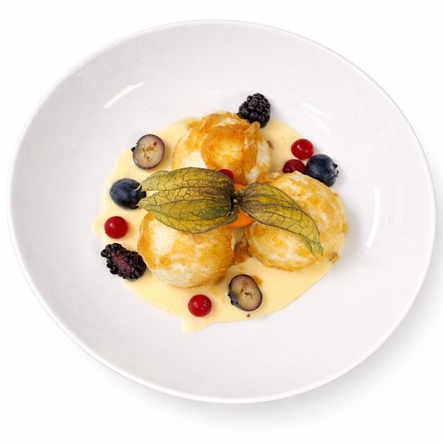 Topfenknödel mit Marillenfüllung, Vanillesauce und süßen Bröseln 